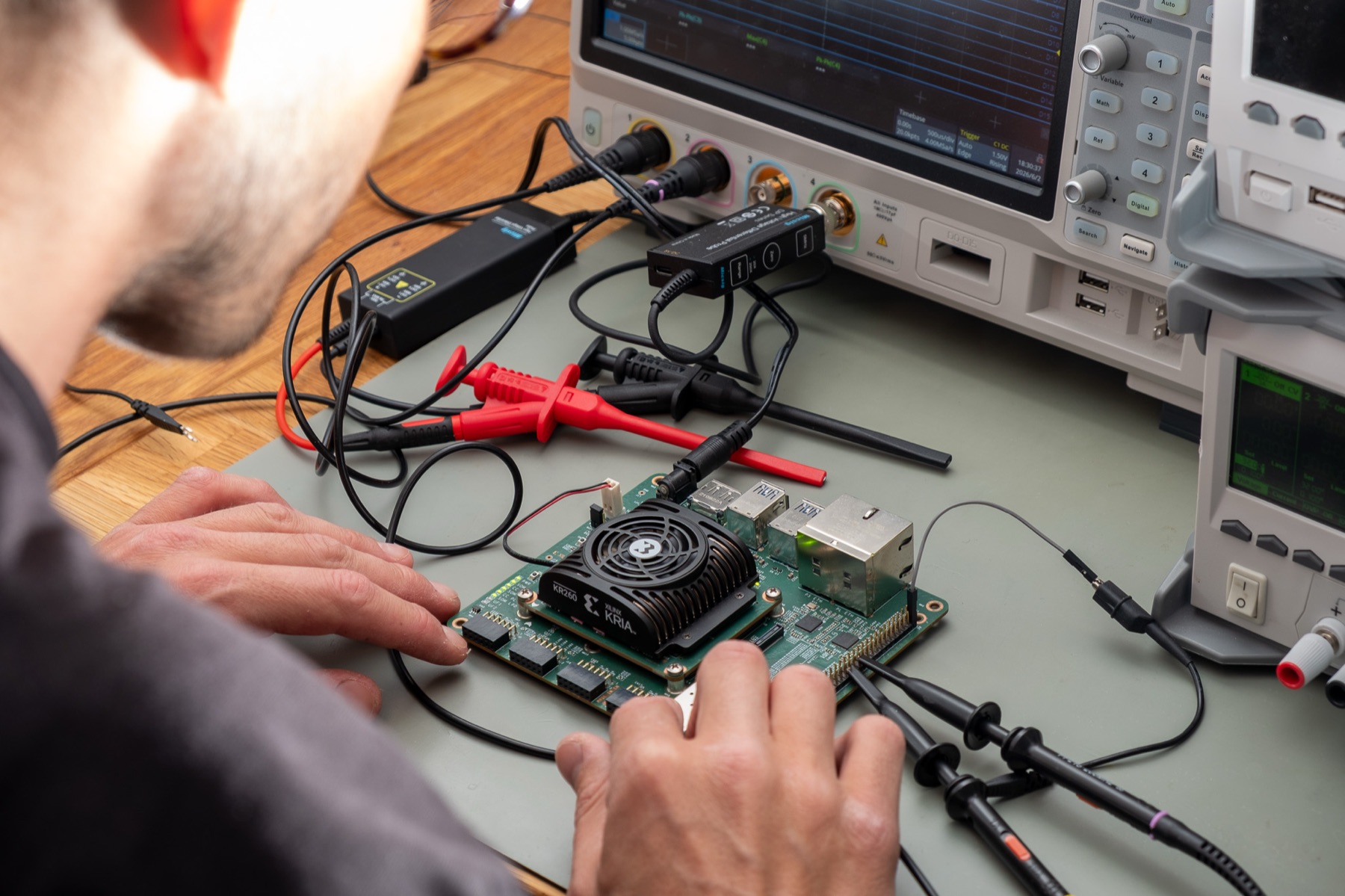 Probing a Xilinx Kria FPGA module on the bench, oscilloscope in the background